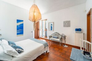Ein Schlafzimmer mit Bett, Pendelleuchte, Stuhl und Tisch.