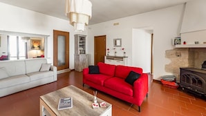 Ein Wohnzimmer mit rotem Sofa, weißem Sofa, Couchtisch aus Holz und Kamin.