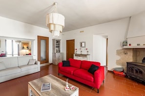 Ein Wohnzimmer mit rotem Sofa, weißem Sofa, Couchtisch aus Holz und Kamin.