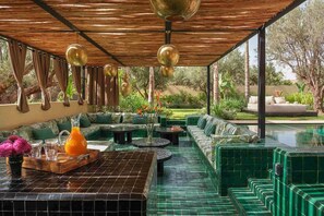 A covered outdoor seating area with a pool, green tiled flooring, and a view of the garden. - Villa Jeddi - Eight Bedroom Villa, Sleeps 20 (Sidi Youssef Ben Ali)