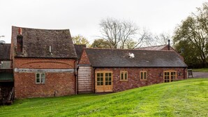 A brick building with a sloped roof, a large wooden door, and a small window.