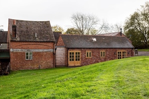 A brick building with a sloped roof, a large wooden door, and a small window.