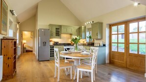 A kitchen with wooden flooring, a dining table with chairs, and a refrigerator.