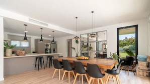 Een moderne keuken met een houten eettafel, zwarte stoelen en hanglampen.