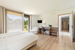A hotel room with a bed, desk, chair, TV, and a view of the outdoors. - Villa SP1 Suites Santa Ponsa pool wifi (Santa Ponsa)