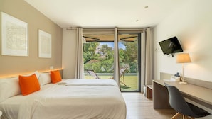 Een hotelkamer met een bed, een bureau, een televisie en uitzicht op de omgeving.