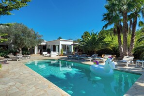 A swimming pool with lounge chairs and a unicorn float. - Villa Can Colomaret Carmen (Ibiza)