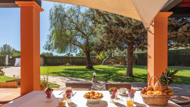 Een terras met eethoek, gedekt voor het ontbijt, inclusief fruit, gebak en drankjes.