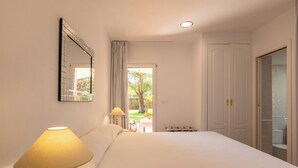 Een hotelkamer met een bed, een lamp, een spiegel, een deur en uitzicht.