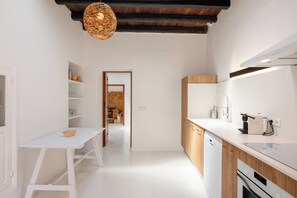 A modern kitchen with white cabinetry, a wooden countertop, and a hanging light fixture. - New! Villa Plana Menut (Can Escandell)