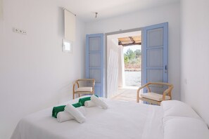 A hotel room with a bed, two chairs, a window, and an open door leading outside. - New! Villa Plana Menut (Can Escandell)