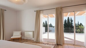 Ein Schlafzimmer mit Bett, Stuhl, Heizkörper und Blick ins Freie.