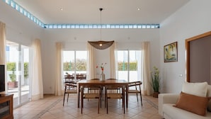 Ein geräumiges Wohnzimmer mit Essbereich, großen Fenstern und Blick ins Freie.