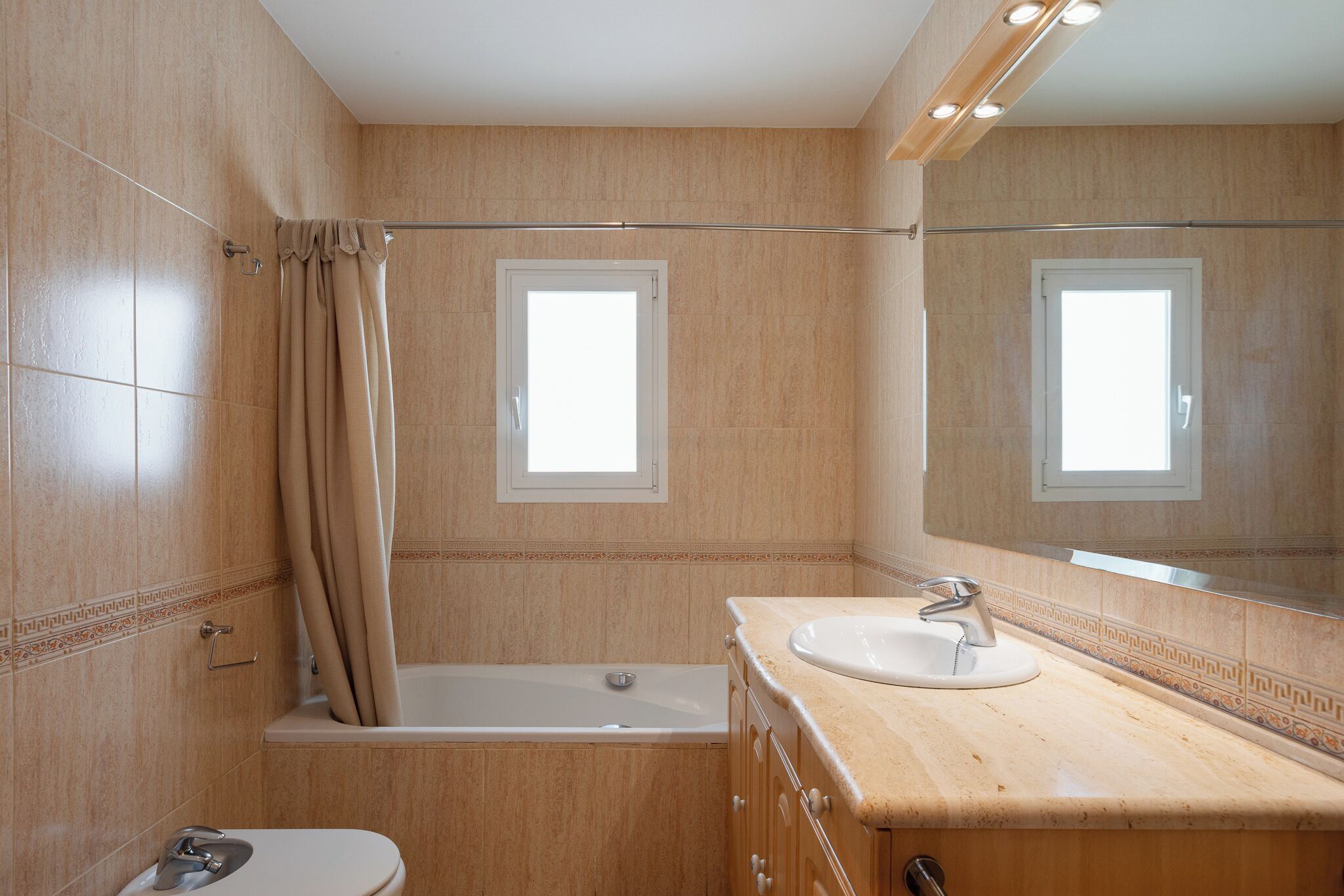 Une salle de bain avec une baignoire, des toilettes, un lavabo et un grand miroir.