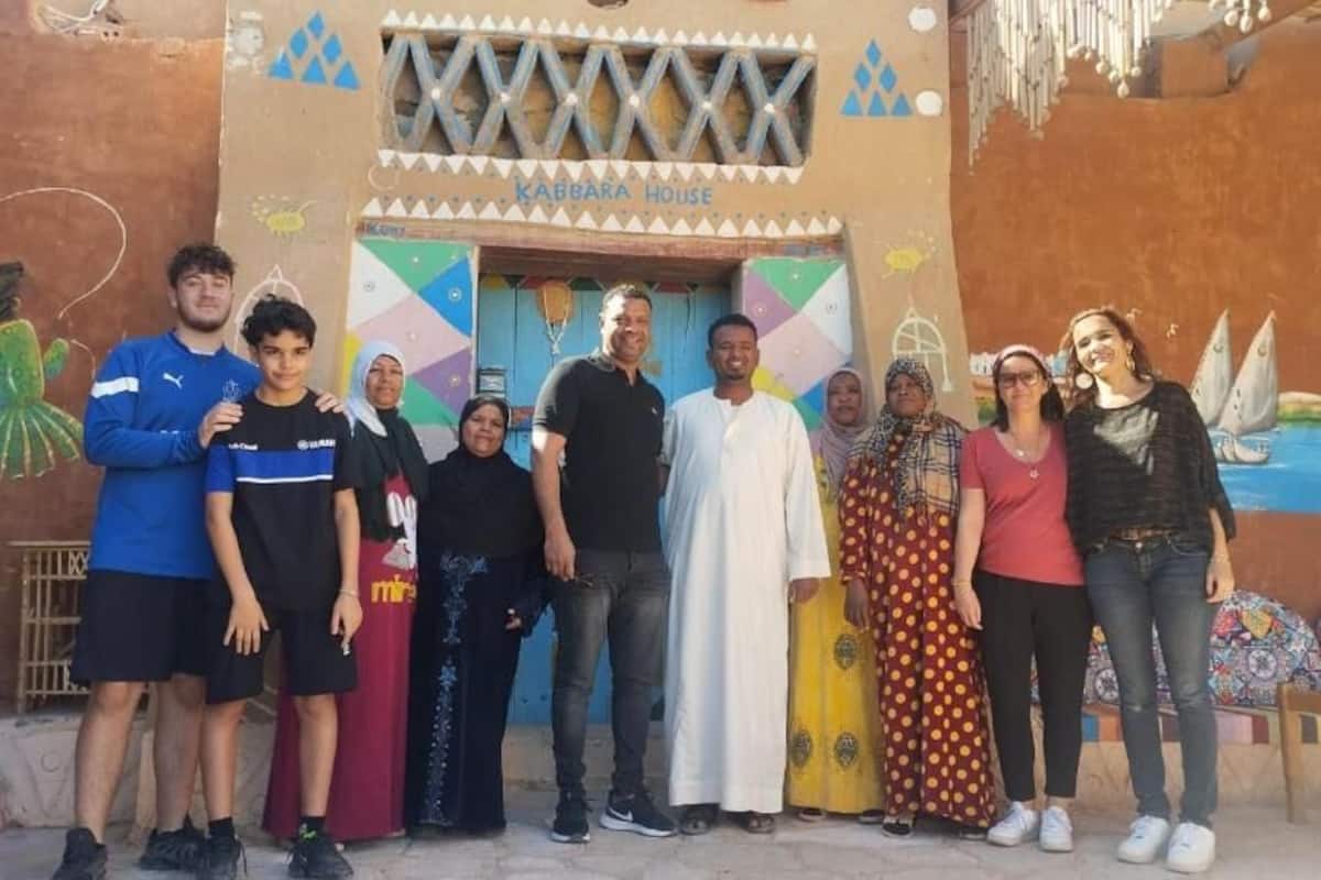 A group of people standing in front of a building with a mural and a sign that reads 'KABBARA HOUSE.'
