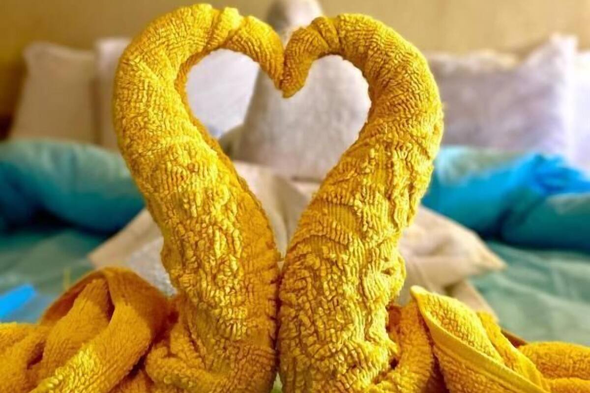 A bed with a heart-shaped towel arrangement.