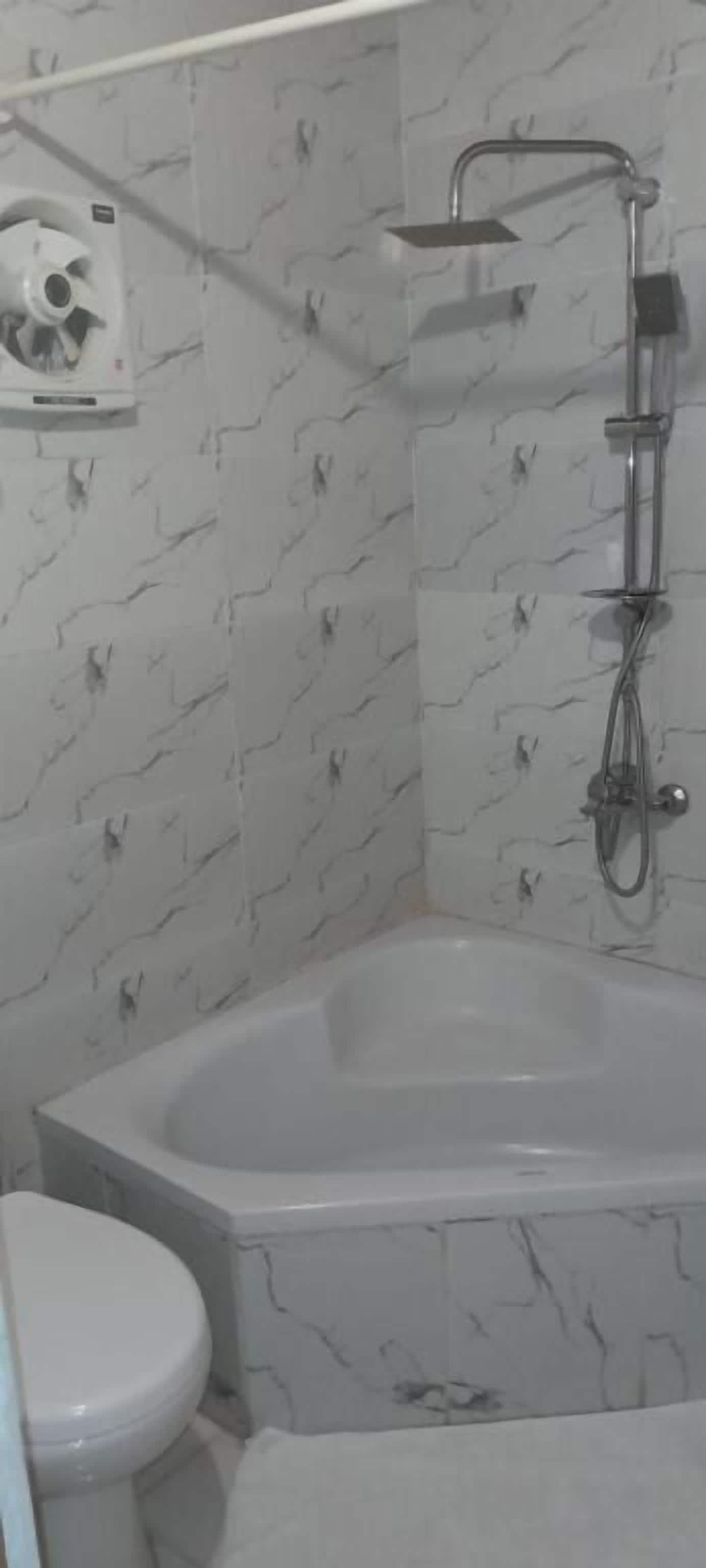 A bathroom with a bathtub, toilet, and a showerhead.