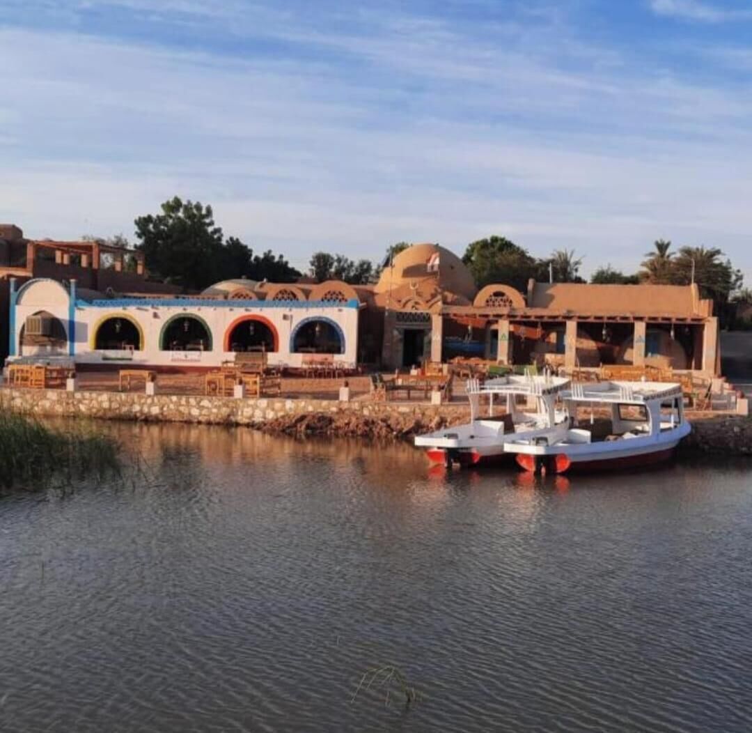 Un hotel sul lungomare con un molo, barche e un edificio con diverse arcate.