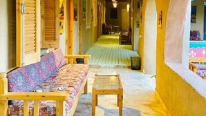 A corridor with a wooden bench, a sofa, and a table. - Kabara (Abu Simbel)