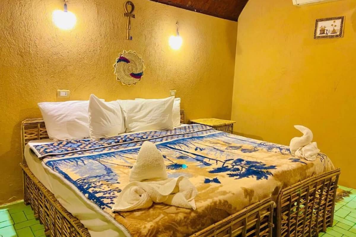 A room with a bed, a wall clock, and a small table.
