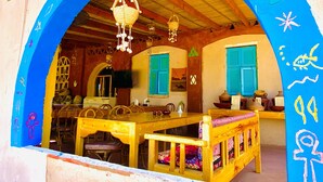 A room with a wooden table, benches, and a hanging basket. - Kabara (Abu Simbel)