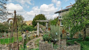 A garden with a stone wall, wooden structures, and a variety of plants. - Apartment “Wintergarten Am Thingplatz” with Shared Terrace, Garden & Wi-Fi (Rinteln)