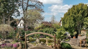 A garden with a wooden bridge, potted plants, and outdoor furniture. - Apartment “Wintergarten Am Thingplatz” with Shared Terrace, Garden & Wi-Fi (Rinteln)
