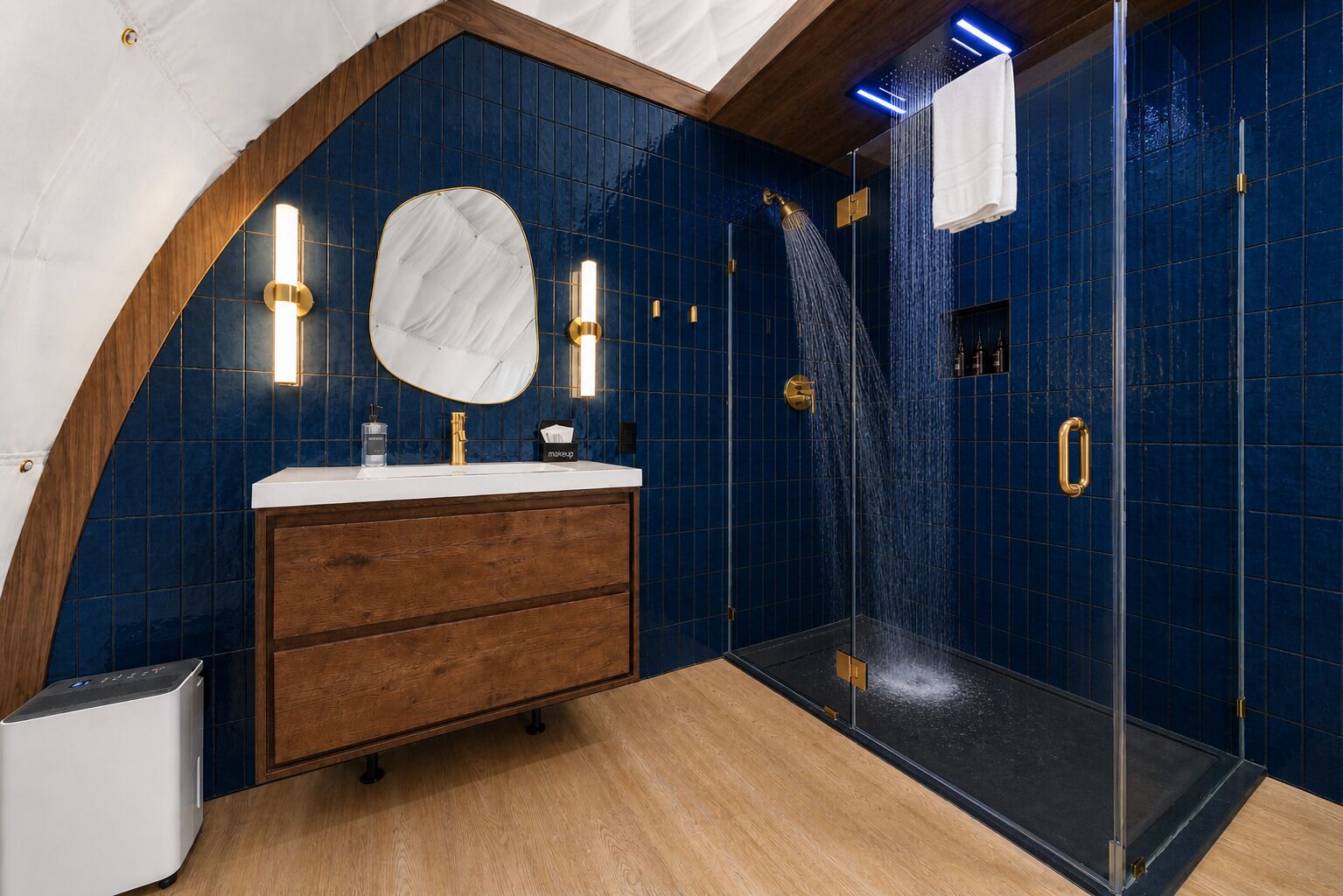 A modern bathroom with a curved ceiling, a shower with a glass door, a vanity with a mirror, and blue-tiled walls.