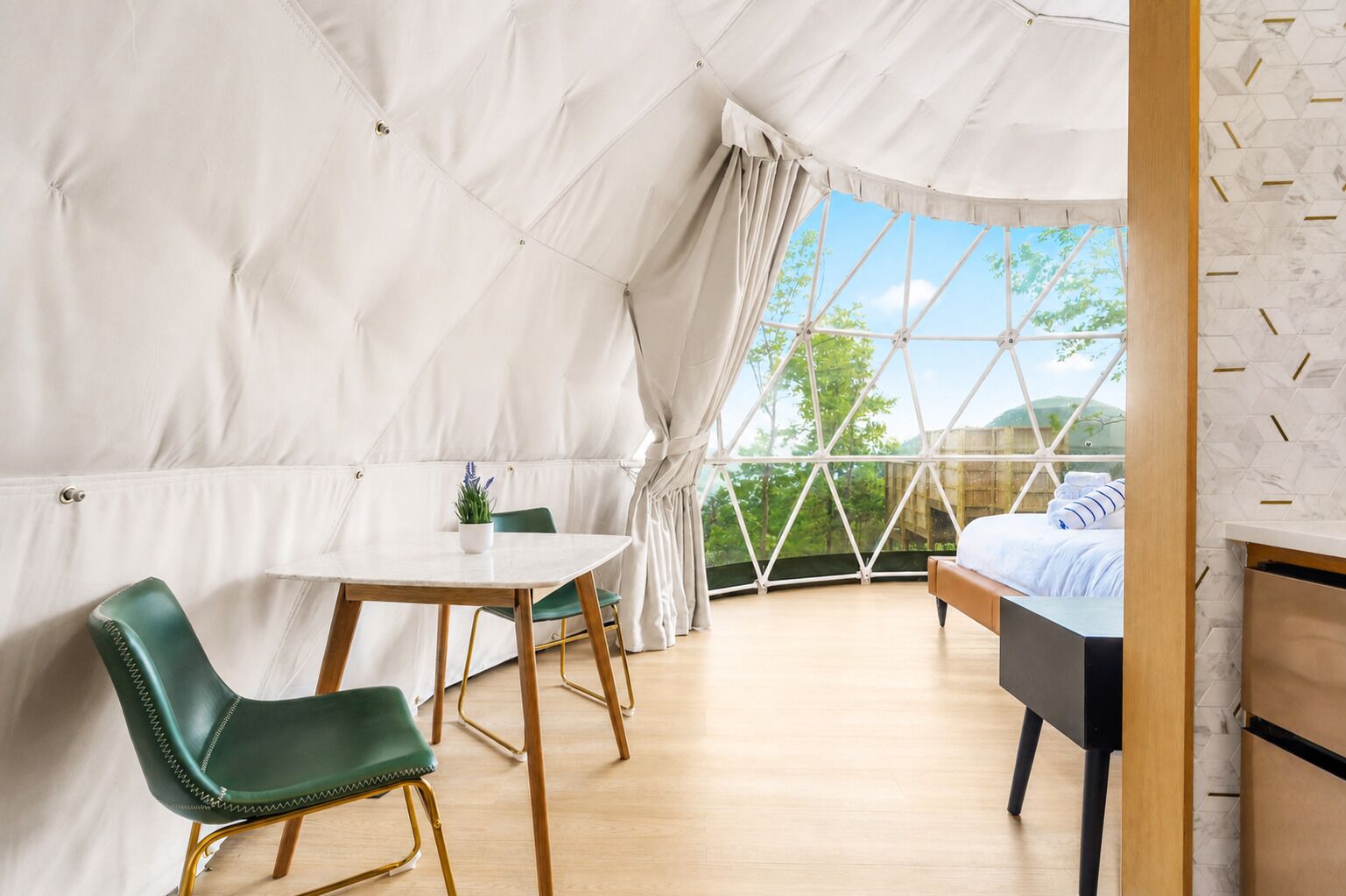 A tented room with a bed, a table, and chairs.