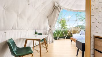 A tented room with a bed, a table, and chairs.