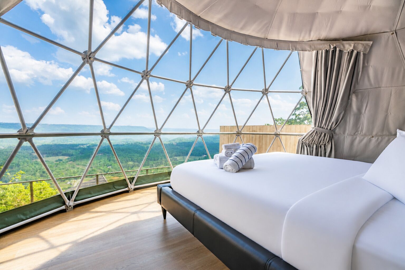 Une chambre dotée d’une grande fenêtre, d’un lit et offrant une vue sur un paysage verdoyant.