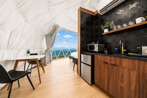 A tented accommodation with a kitchen area, a dining table, and chairs.