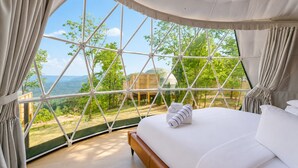 A bedroom with a large window, a bed, and curtains. - Glamping Collective Chattanooga (Trenton)