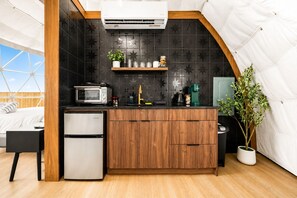 Eine kleine Küche mit Mikrowelle, Toaster und Kaffeemaschine, einem kleinen Kühlschrank und einem Blumentopf.