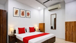 Une chambre d’hôtel avec un lit en bois, des murs blancs et une touche de couleur rouge.