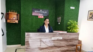 Un comptoir d’accueil avec une enseigne indiquant « MAHARAJA inn » et un panneau « DÉFENSE DE FUMER ».