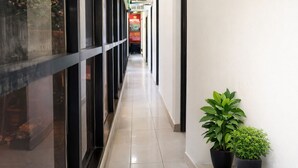 Un couloir avec des portes vitrées, un sol carrelé et des plantes en pot.