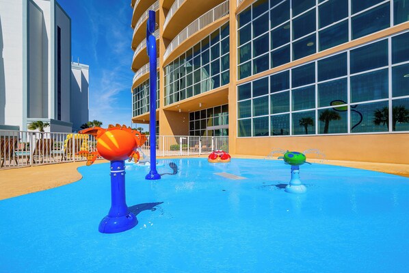 A water play area with various water features and a building with large windows in the background. - Phoenix Orange Beach II 505 Luxury Corner Gulf Condo  Lazy River Resort (Orange Beach)