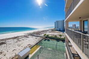 A beach view from a balcony with a tennis court and a building in the background. - Phoenix X 602  Gulf-Front Condo Sleeps 6  King Bed + Bunks (Orange Beach)