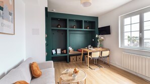 Un espacio habitable moderno con sofá, mesa de comedor, sillas, televisor y ventana.