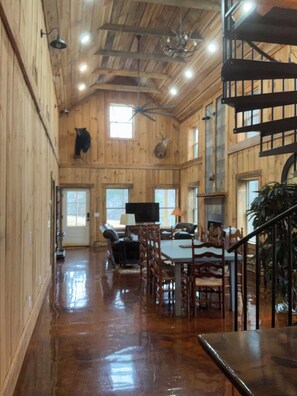 A spacious interior with wooden walls, a dining area, a staircase, and a mounted animal head. - Cozy 4-bedroom cabin in the Appalachian mountains of peaceful Tuckasegee, NC (Tuckasegee)