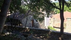 Ein Gebäude aus Stein mit Ziegeldach, umgeben von Bäumen und einer Steinmauer.