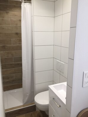 Un baño con ducha, inodoro y lavamanos.