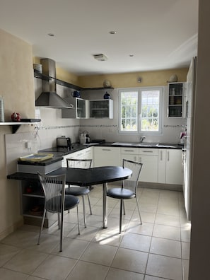 Une cuisine moderne avec une table à manger, des chaises, des placards et une fenêtre.