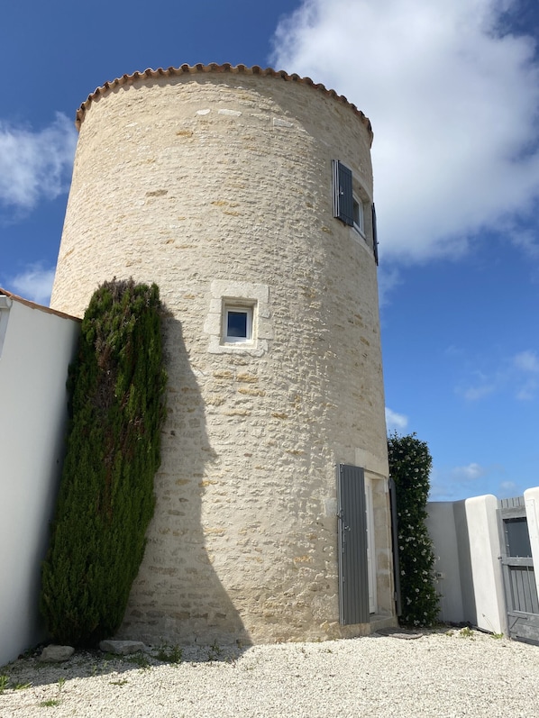Une tour de pierre cylindrique, dotée d’une petite fenêtre, d’une porte et d’un mur percé d’une autre petite fenêtre.