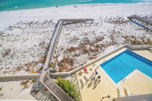 Vista de una playa con piscina, muelle de madera y zona arenosa de vegetación escasa.