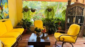 Une pièce dont le mobilier est jaune, avec une table basse en bois et diverses plantes en pot.
