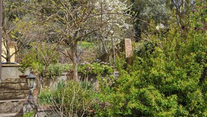 A garden with a stone wall, a lamp post, and various plants. - Il Glicine (Laconi)