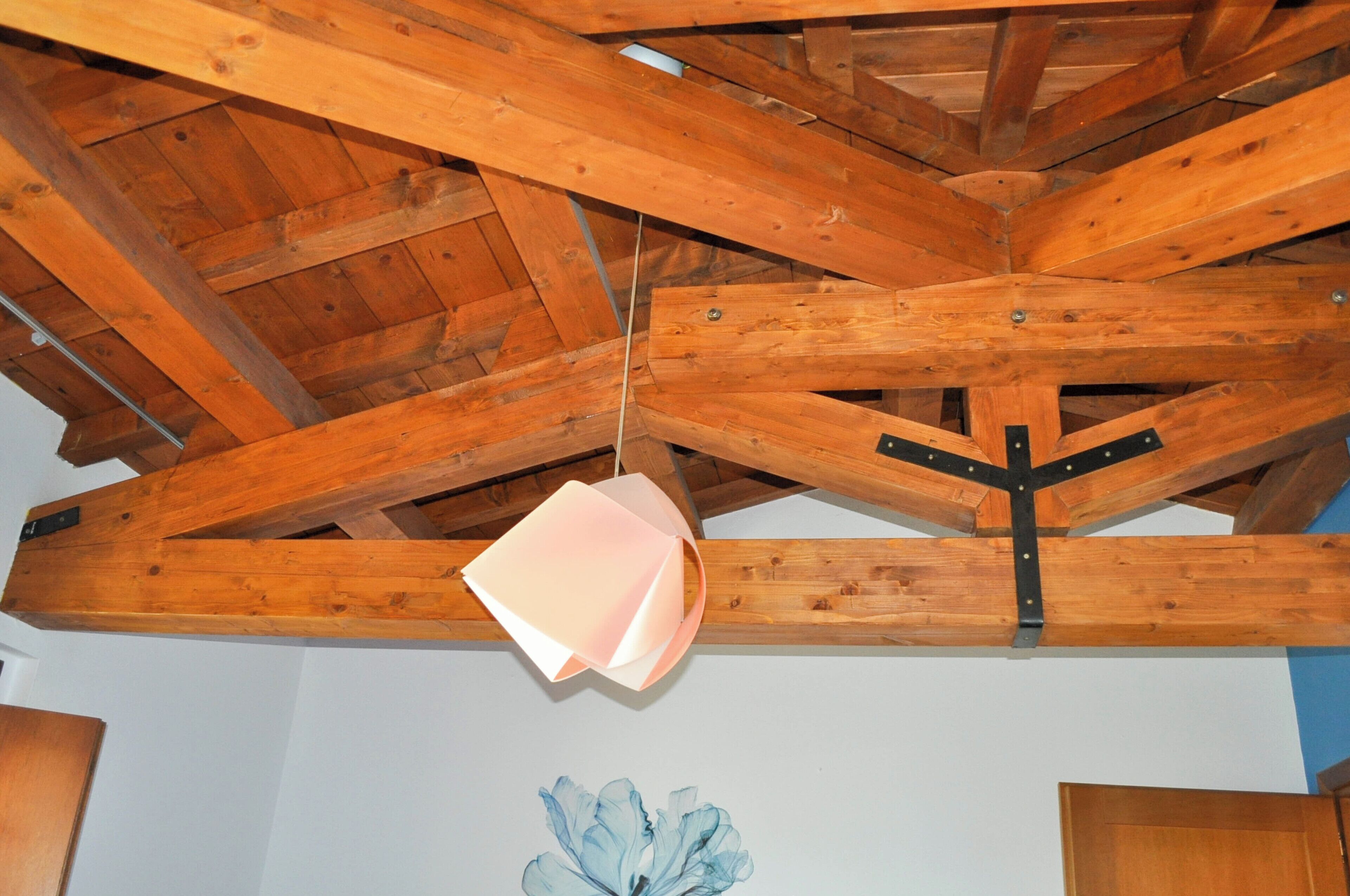 A wooden ceiling with exposed beams and a hanging light fixture.
