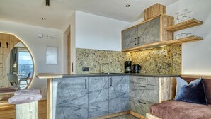 Une cuisine compacte dotée d’un plan de travail en marbre, de meubles en bois et d’un espace dédié à la préparation du café.